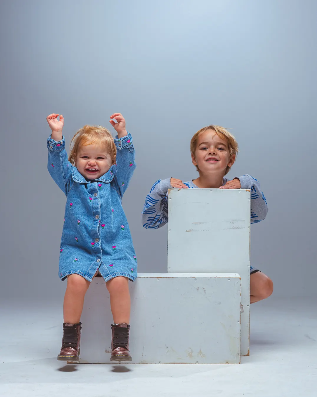 Twee kinderen met de armen omhoog in de studio